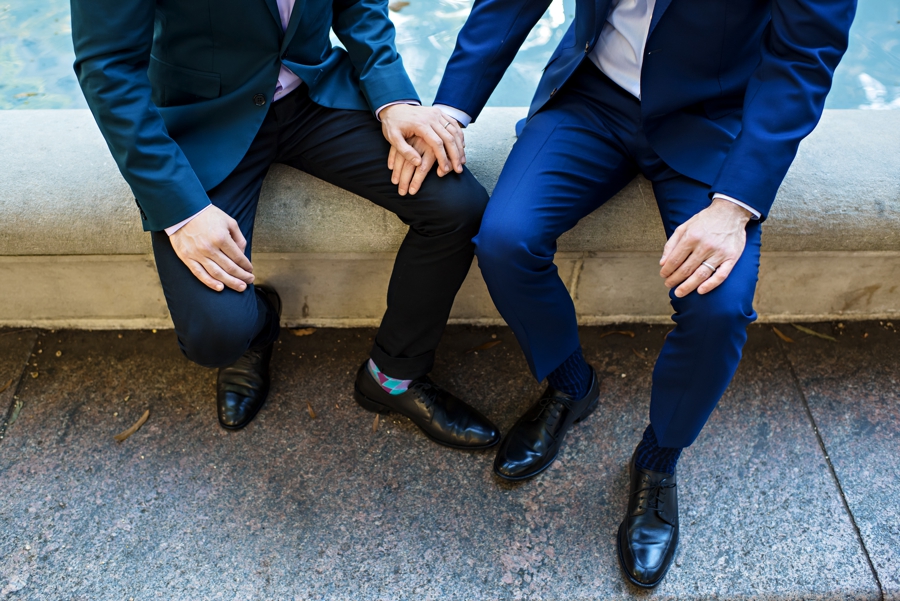 Two men in suits hold hands during their gay engagement session.